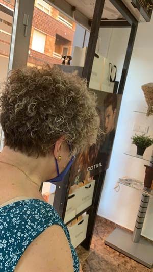 Mujer presentando resultado de acabado de peinado en pelo rizado corto