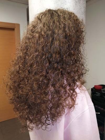 Acabado de peinado en pelo largo rizado visto desde atrás Acabado de peinado en pelo largo rizado visto desde atrás