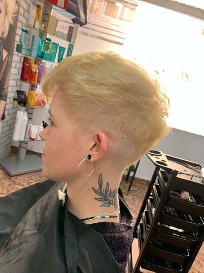 Chica presentando acabado de look con pelo rubio muy corto Chica presentando acabado de look con pelo rubio muy corto